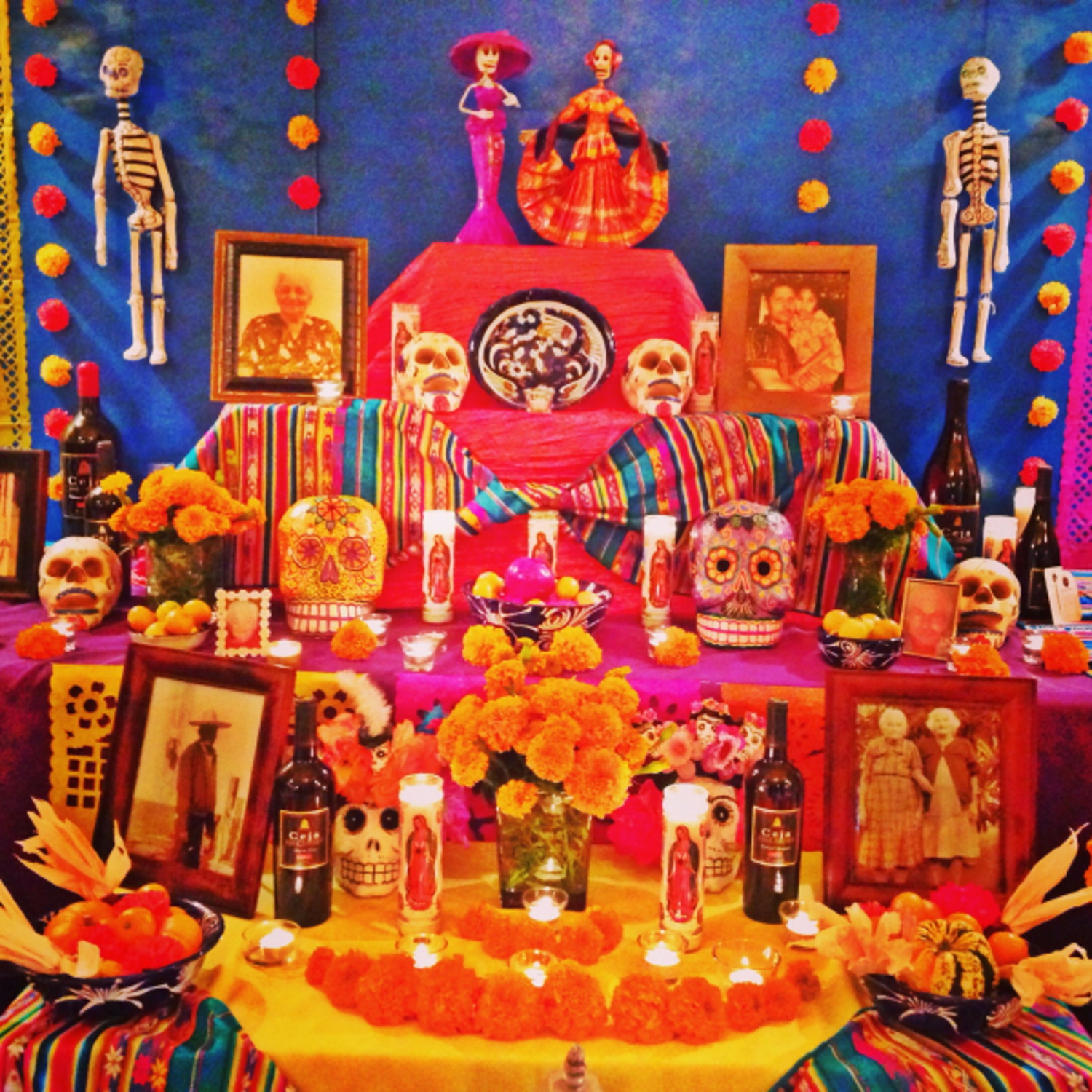 Colorful Dia de los Muertos altar with framed photographs of dead relatives, candles, and more items, dedicated to those who have passed away
