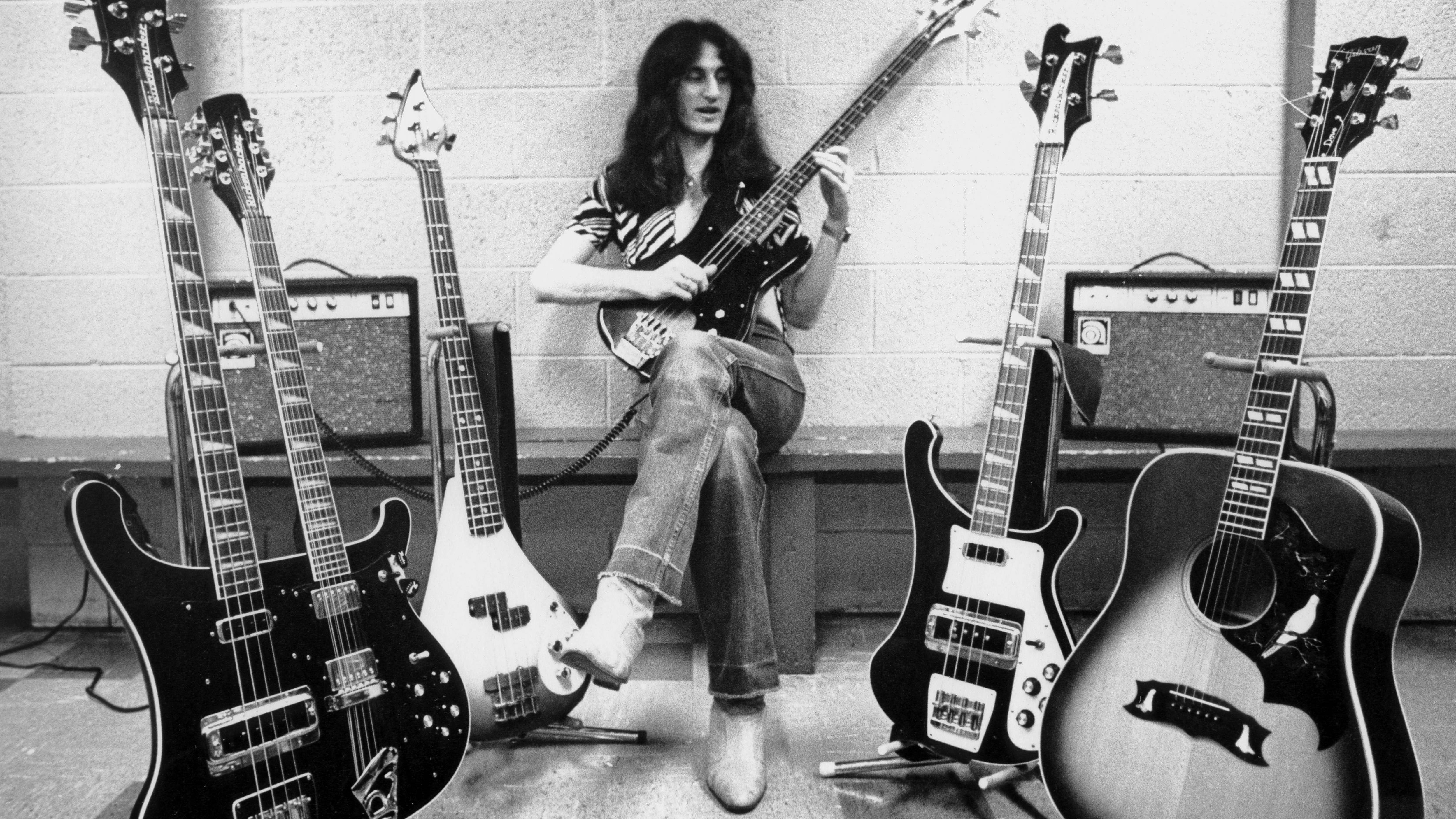 Guitarist of the band Rush, Geddy Lee, posing with his large collection of guitars