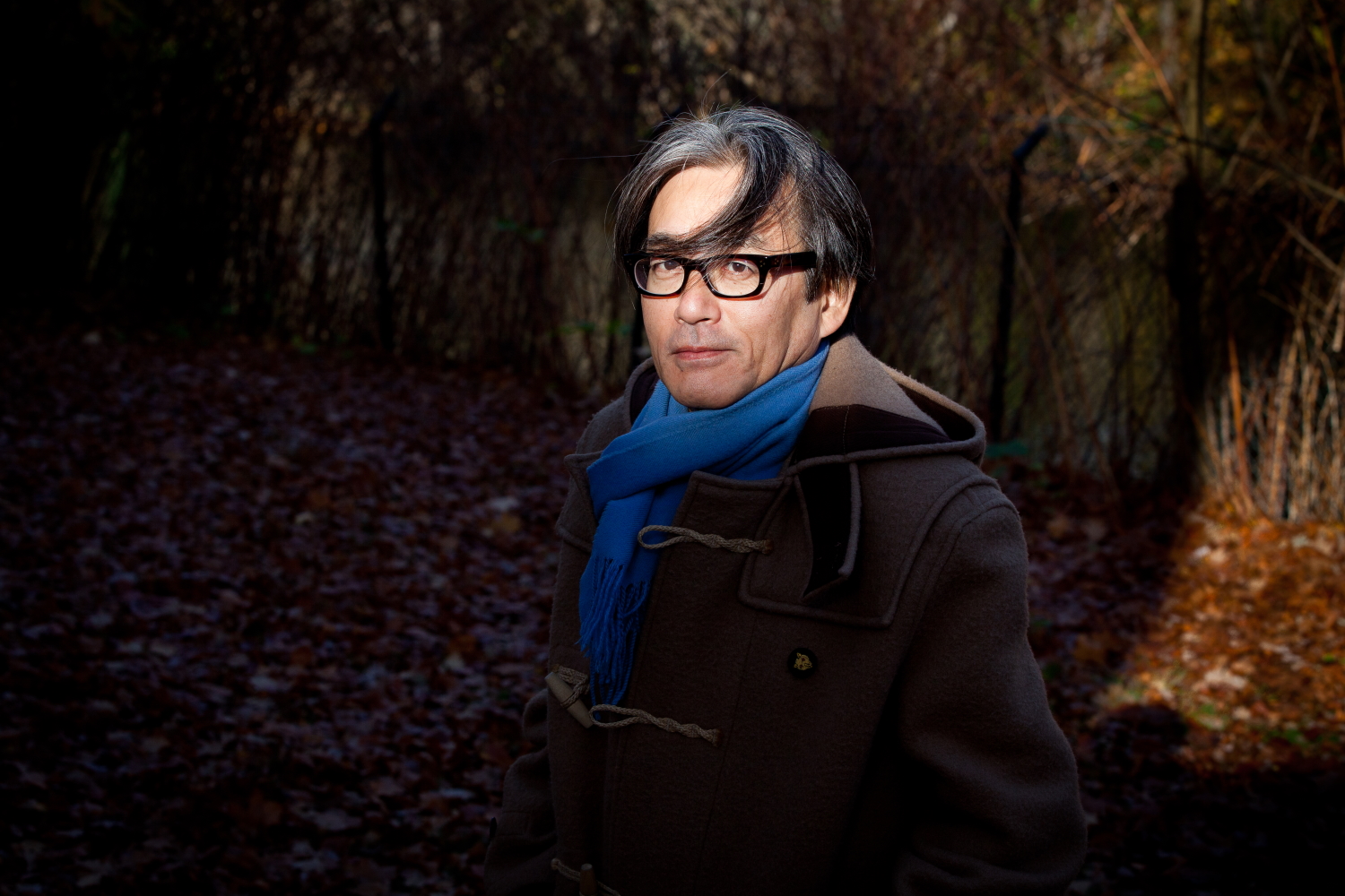 Japanese composer Shigeru Umebayashi posing for a photoshoot in a forest
